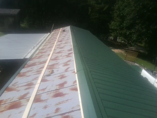 Old rusted panels beside newly installed green metal roofing — Wind Damage Roof Repair by Roofing Brothers in Thorndale