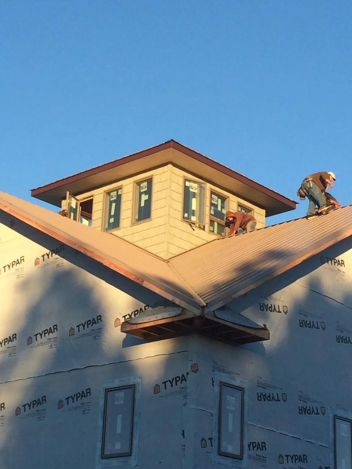 Roofers working around a rooftop cupola on a new metal roof at sunset — Roof Waterproofing in Thorndale by Roofing Brothers